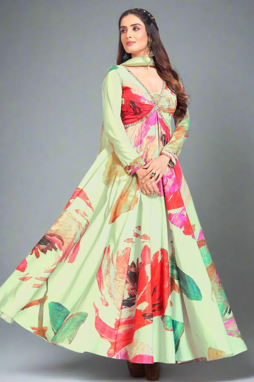 A woman wearing a traditional light green anarkali suit with floral patterns, paired with a dupatta and jewelry.