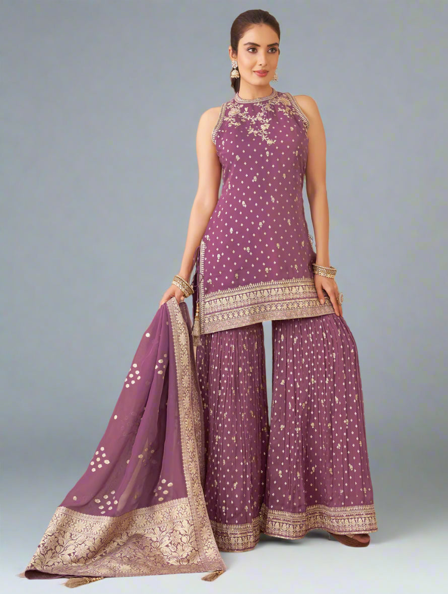 Woman in a purple traditional outfit with white patterns in an indoor setting.