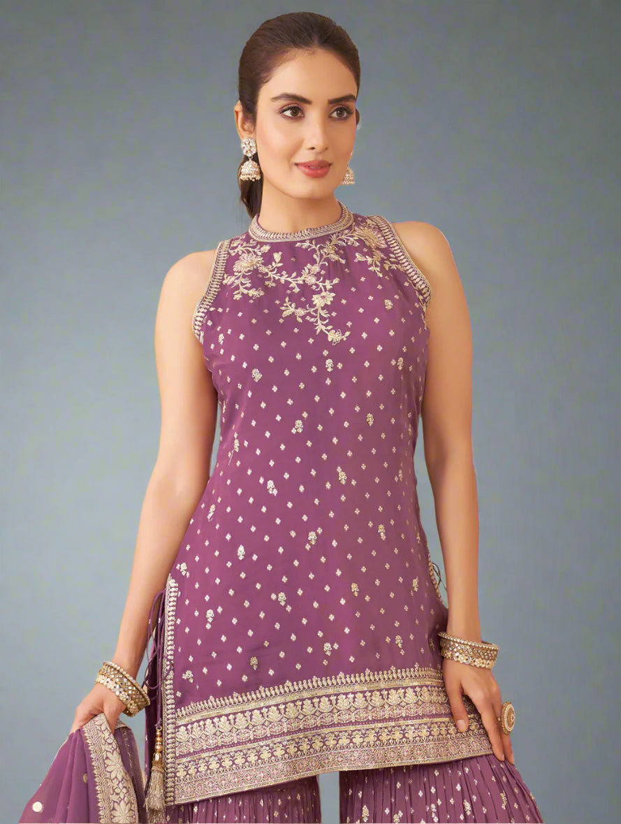 Woman in a purple traditional outfit with white patterns in an indoor setting.