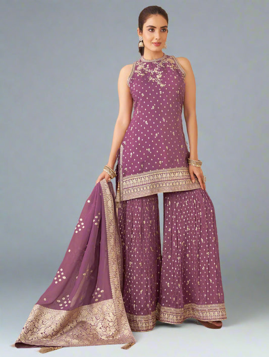 Woman in a purple traditional outfit with white patterns in an indoor setting.